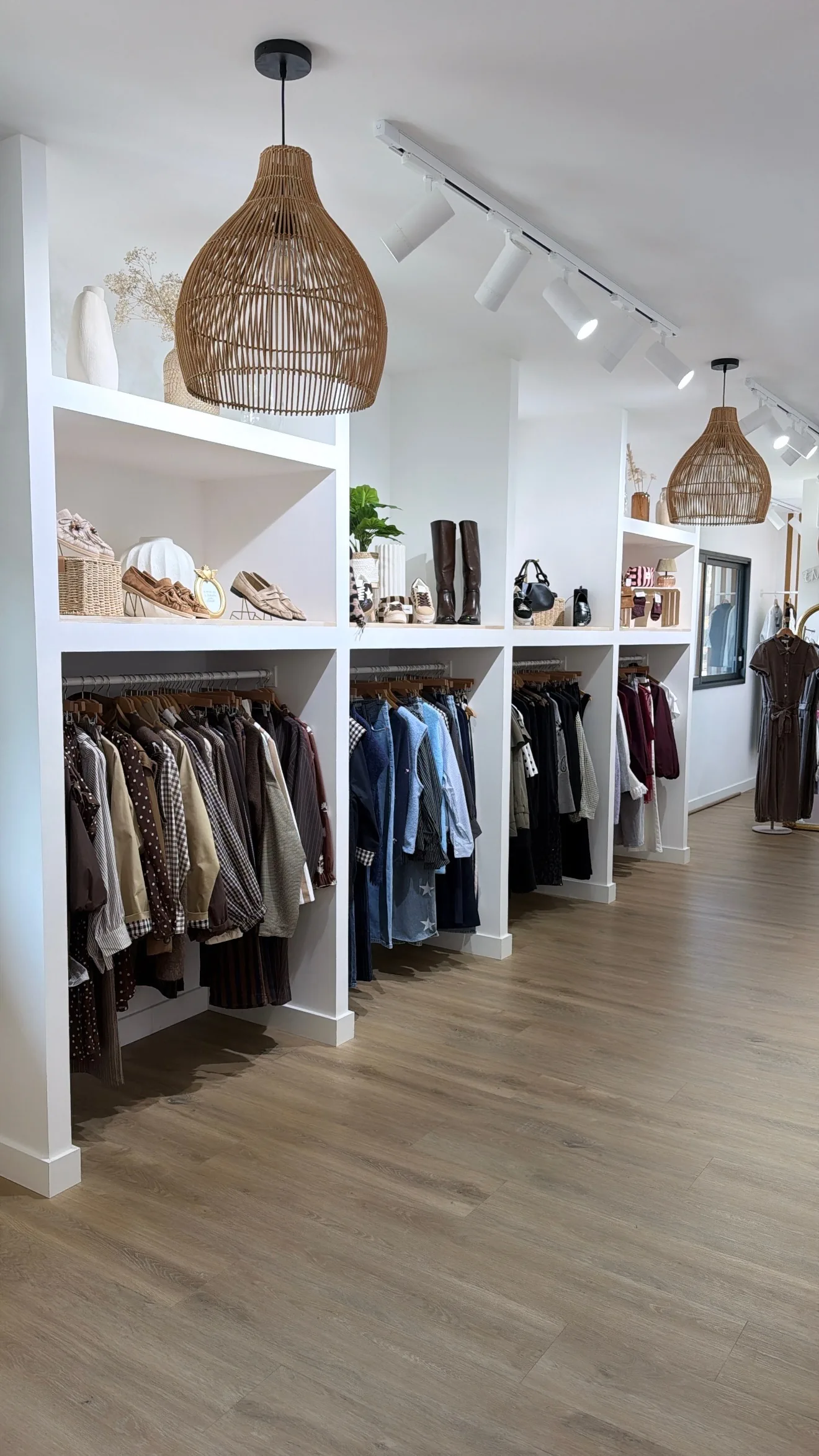 Le rayon prêt-à-porter sous les suspensions en rotin, boutique Atelier Mère & Fille au Houlme